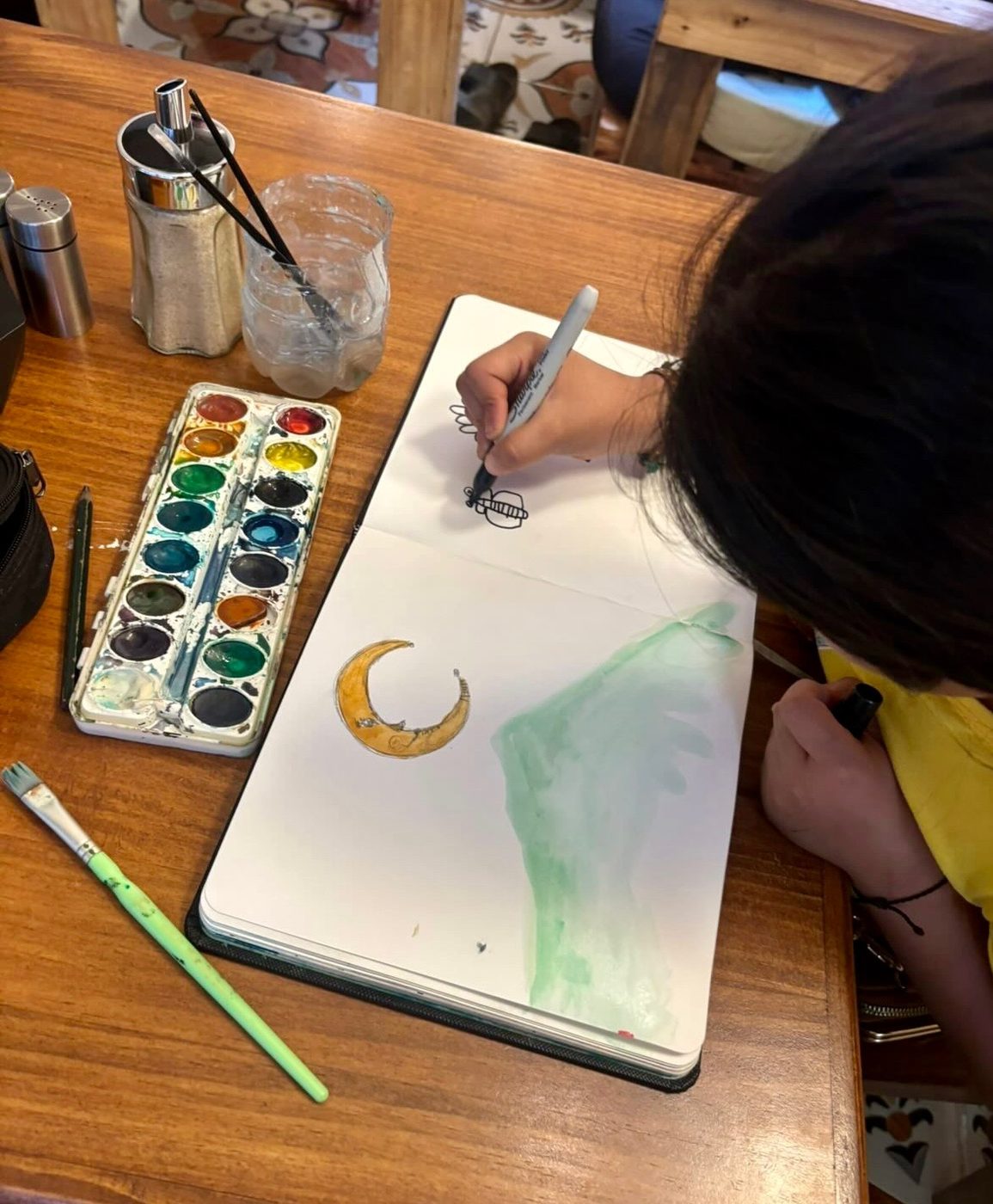 A child drawing in a sketchbook at Espiral